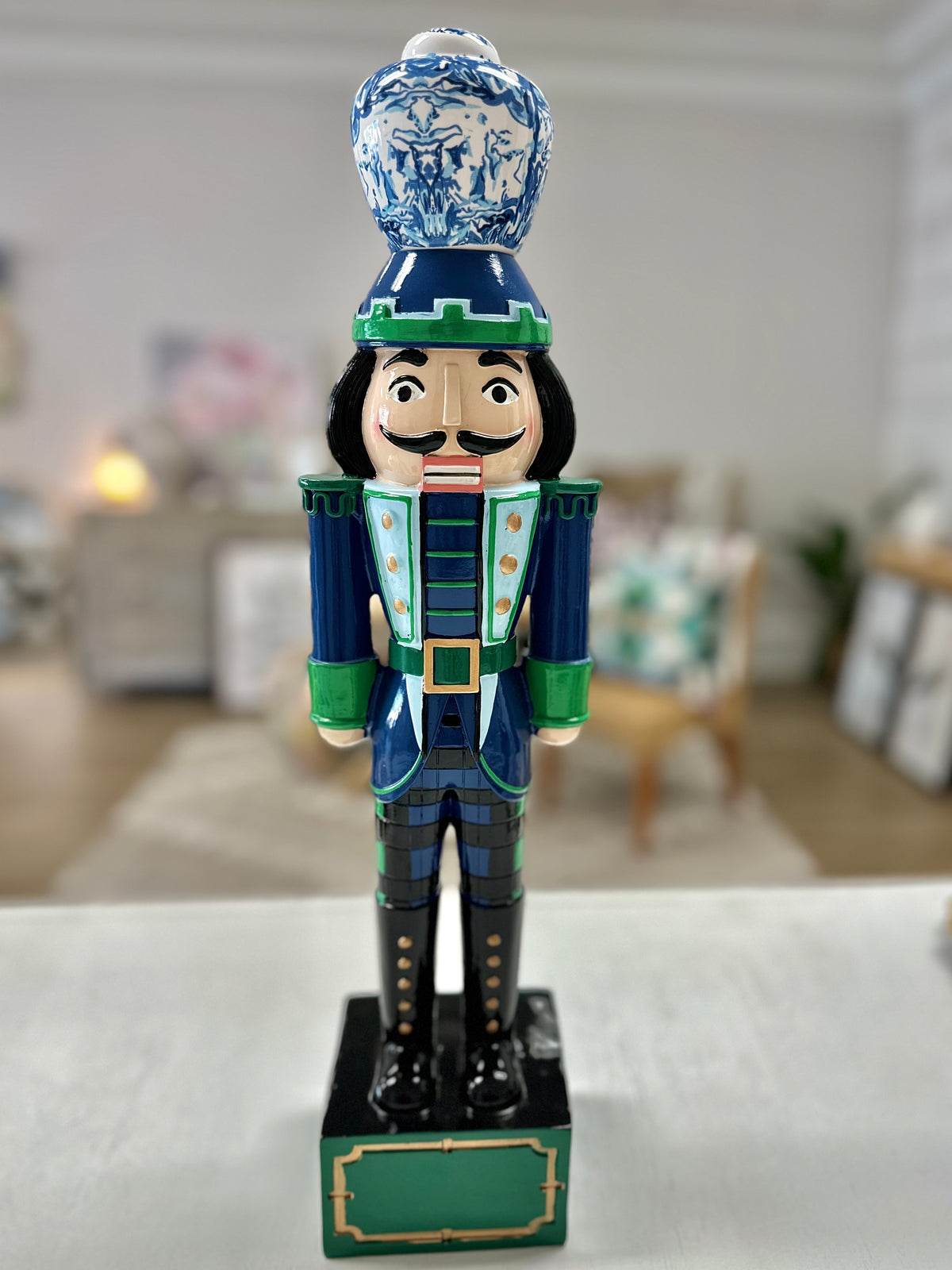 A decorative 19-inch tall nutcracker featuring a hand-painted wooden body in blue and green with a ceramic ginger jar on top.